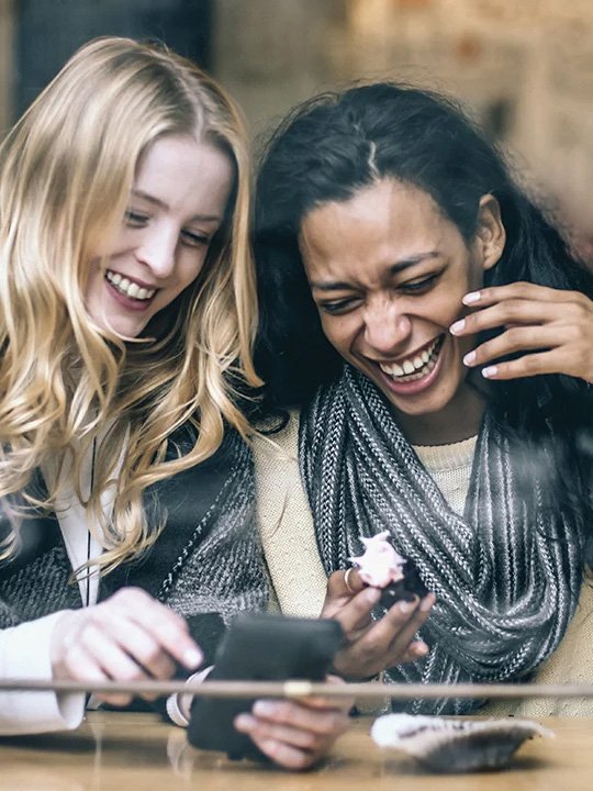 Women talking and laughing looking at a phone