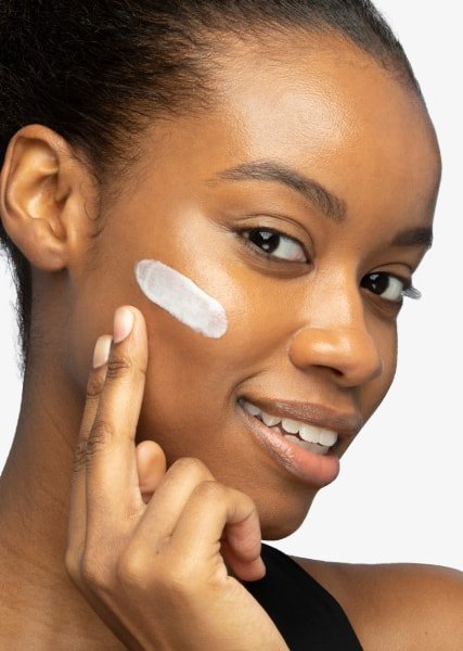 close up of woman’s face applying moisturiser for a glowy clean girl look
