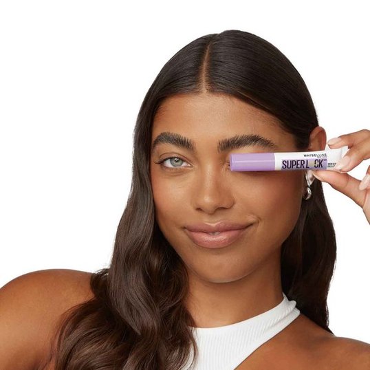 close-up of woman’s face holding the Superlock Brow Glue for a clean girl makeup look
