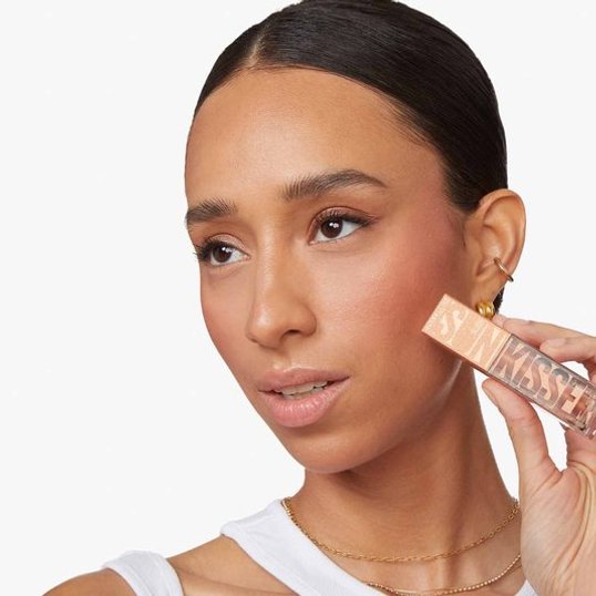 close-up of woman’s face as she holds the Maybelline Sunkisser blush for a clean girl look