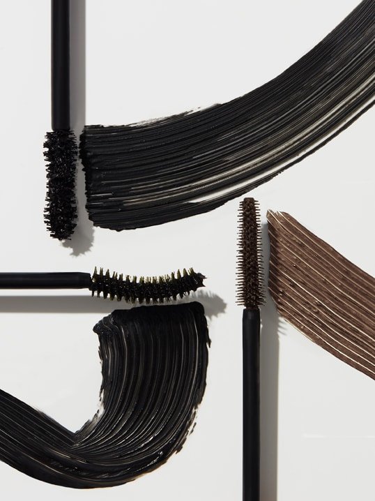 Promotional shot showing Maybelline black and brown mascara wands drawing black and brown coloured lines, with text at the bottom reading: MAYBELLINE MAKEUP DECODED.