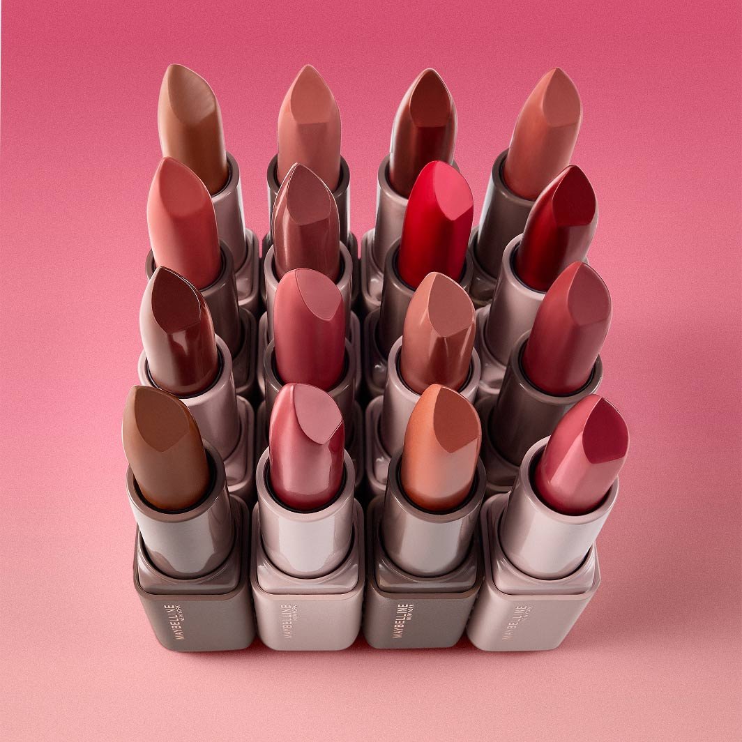 A shot of 16 shades of Maybelline’s Serum Lipstick on a pink background.